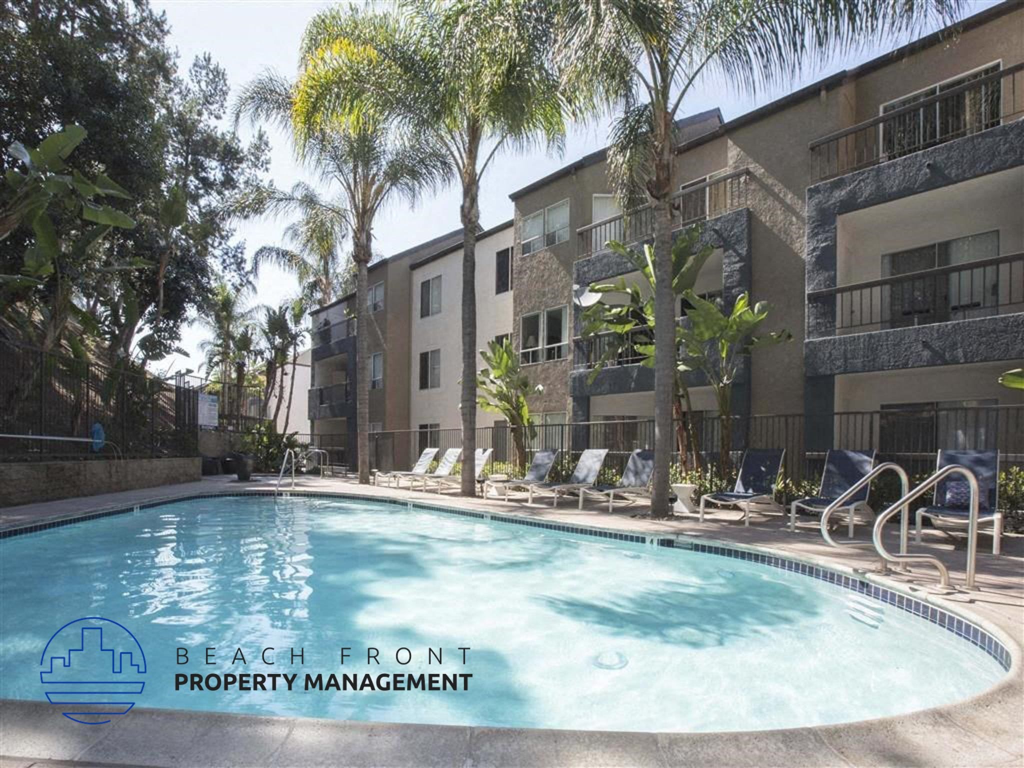 A pool surrounded by palm trees and chairs with the words "Beach Front Property Management" on the bottom left.